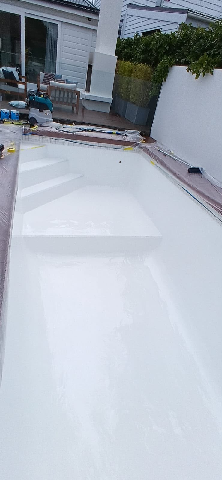 White epoxy coating rolled through the drained pool shell and steps