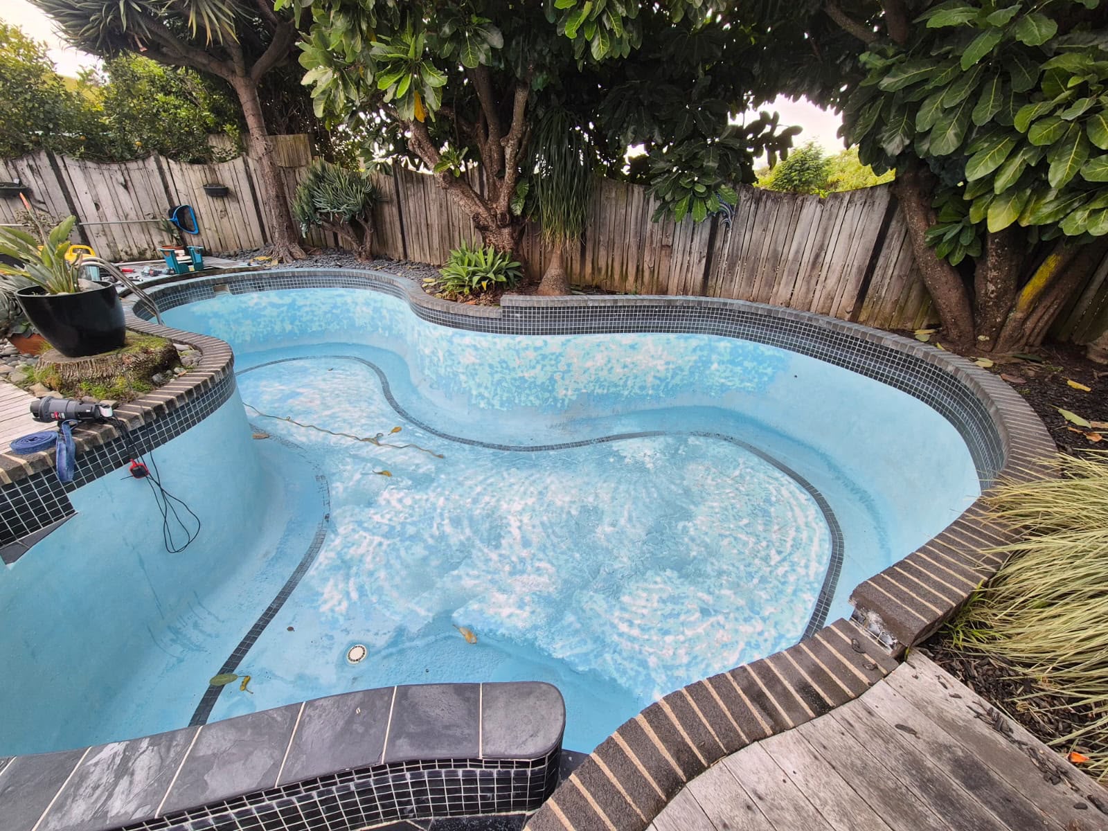 Tired concrete pool with a chalky, patchy pale blue surface before work began