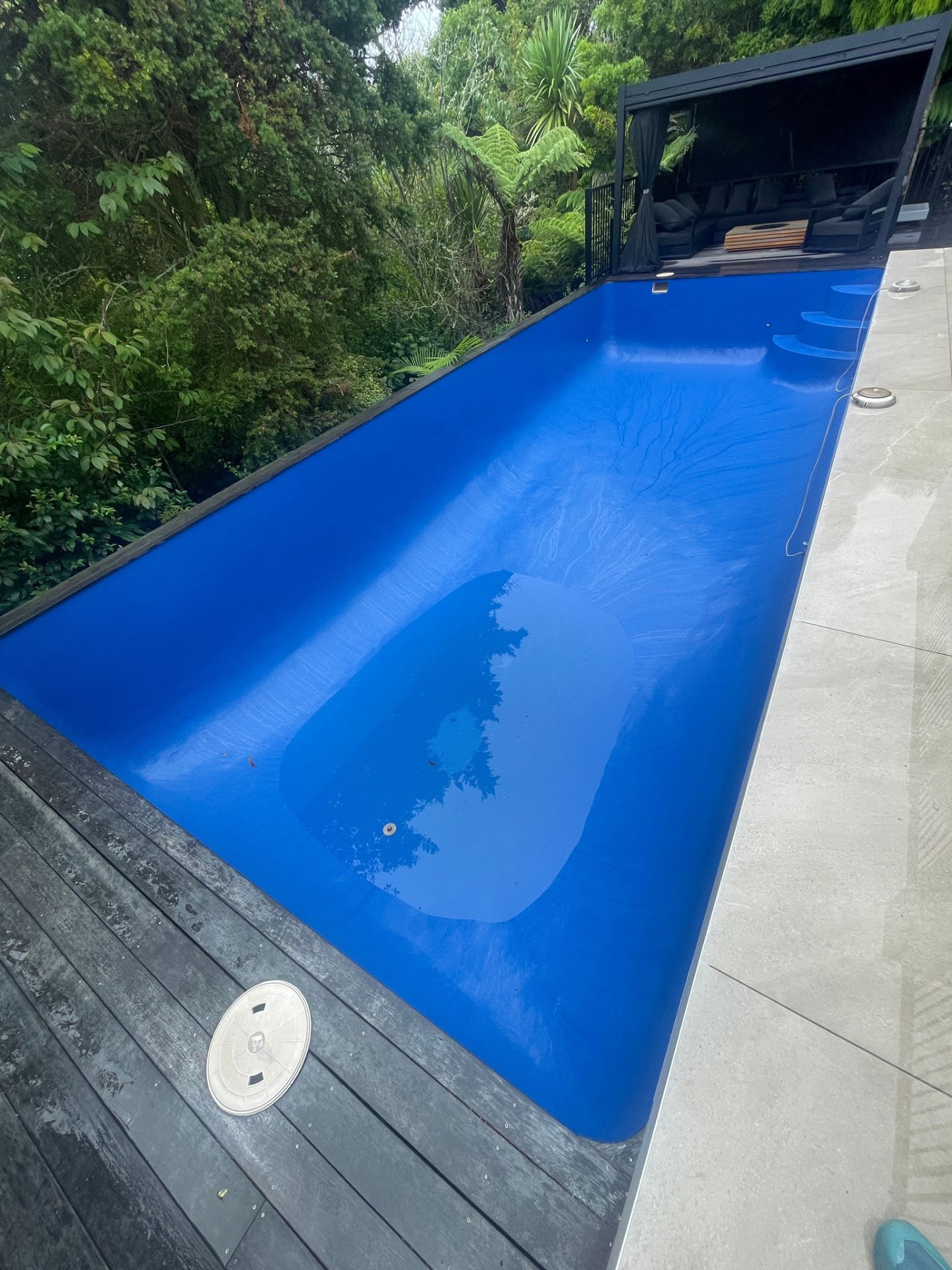 Refilled dark blue pool beside a timber deck and native bush