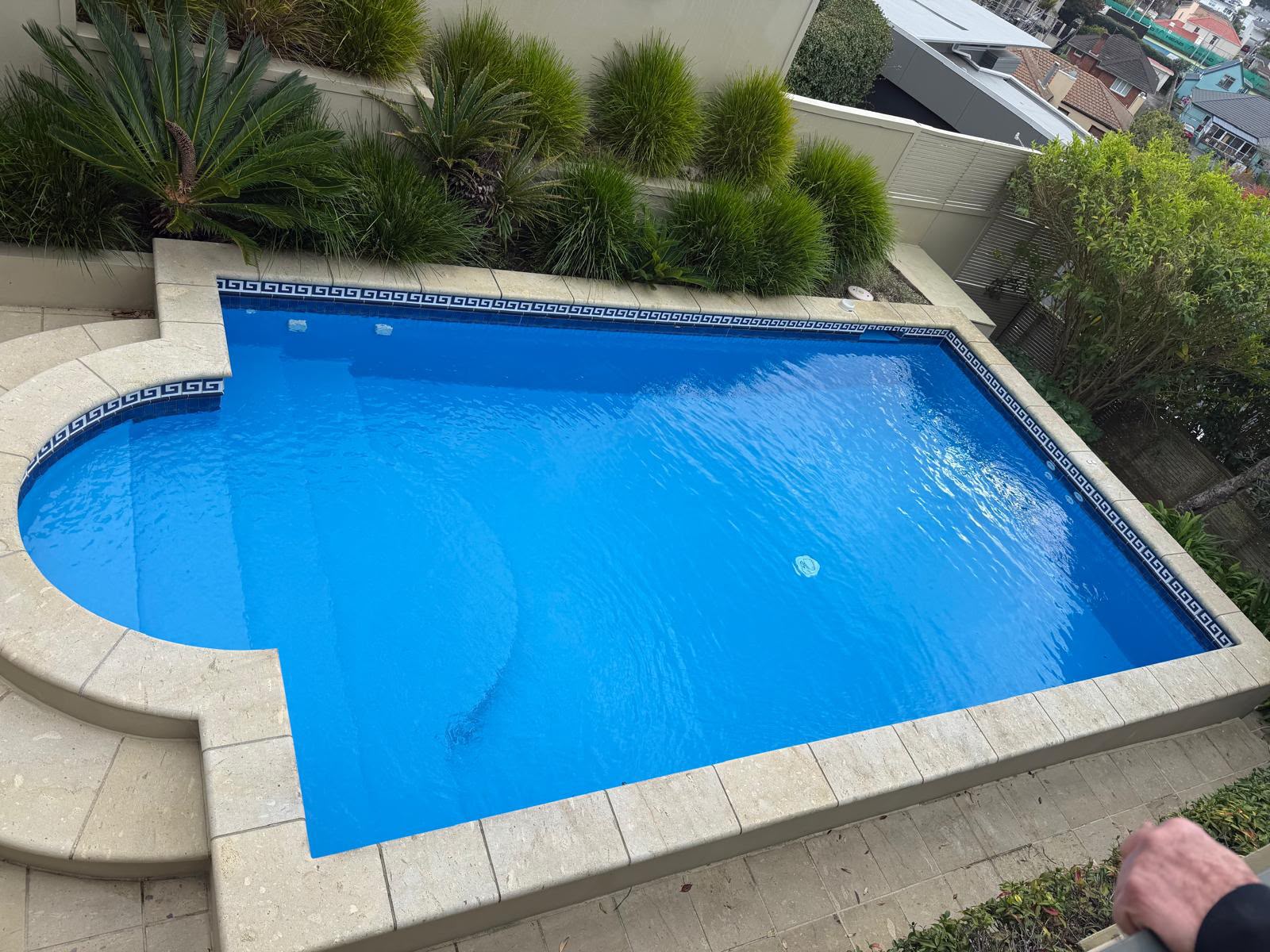Refilled mid blue pool with stone coping and feature tile band