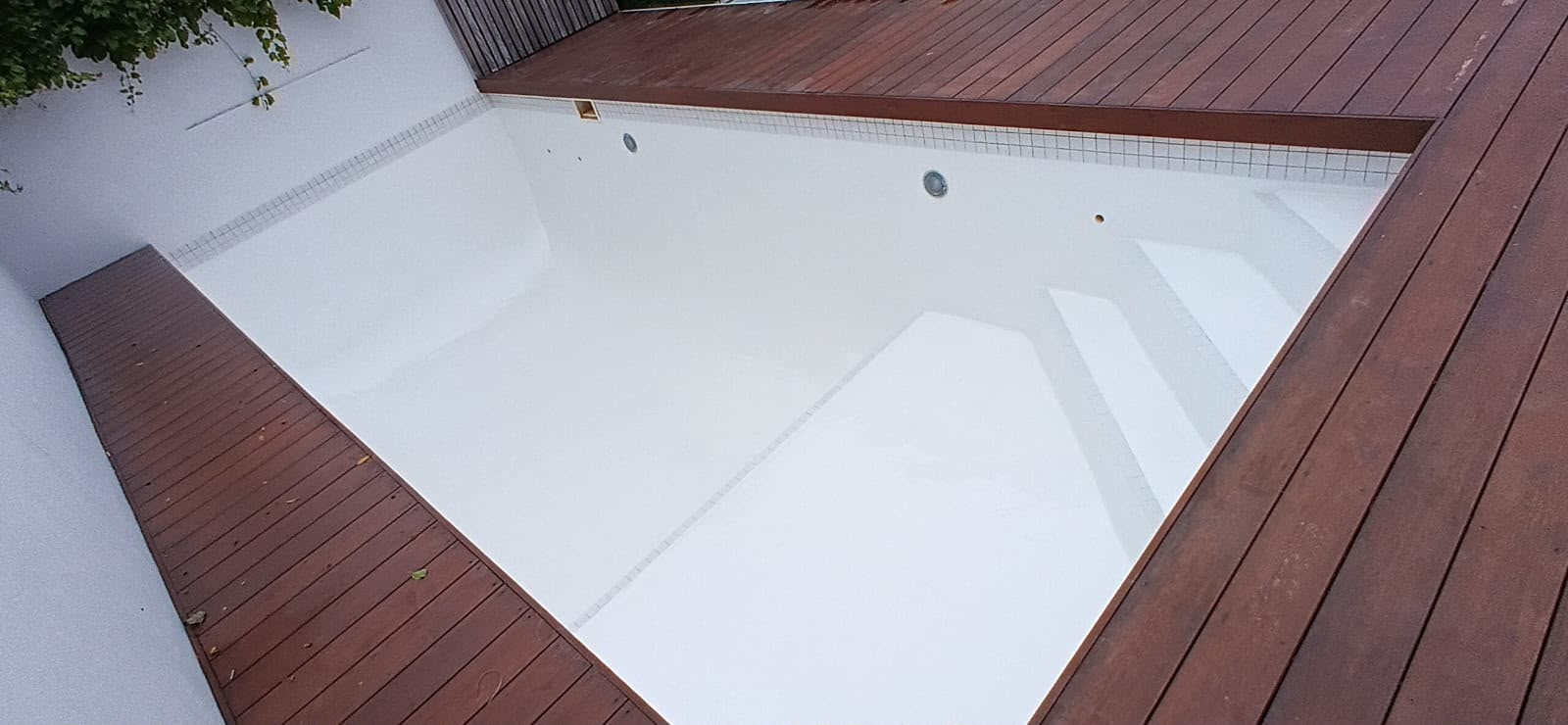 Completed white epoxy pool interior framed by a new timber deck